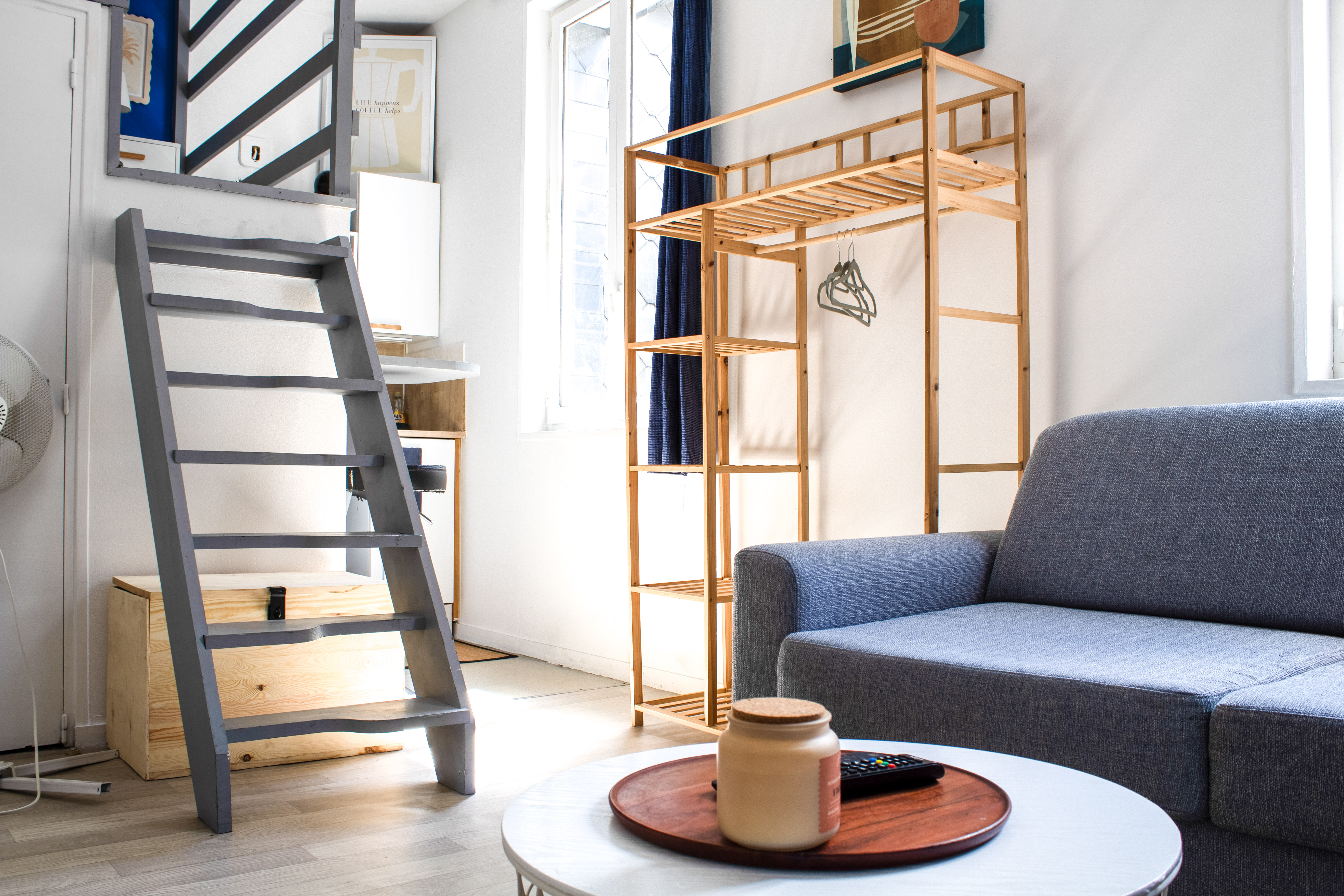 Escalier de mezzanine gris, étagère ouverte en bois et canapé gris au premier plan