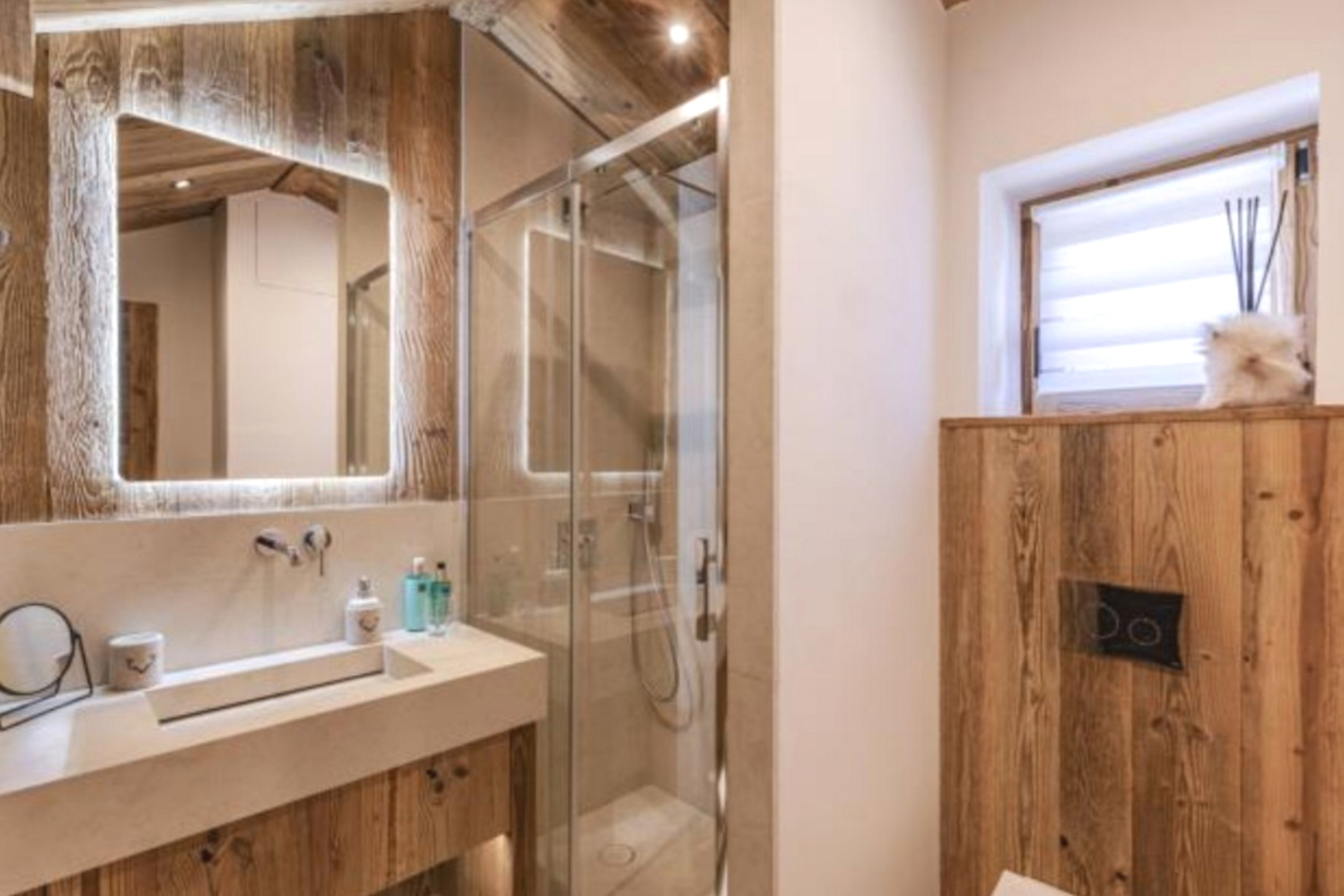 Salle de bain avec vasque encastrée, miroir rétroéclairé, douche à paroi vitrée et WC.